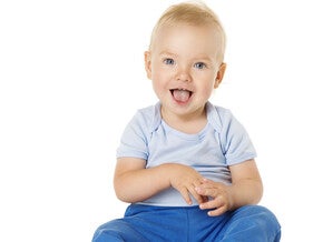 Toddler in blue pants and light shirt, sitting against a white background.