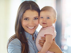 Woman holding a baby in a bright room.