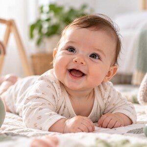 Beba od 4 meseca leži na leđima i pruža ruku prema igrački
