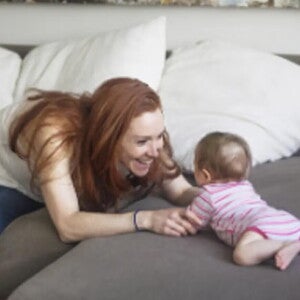 Majka se igra s bebom na krevetu.