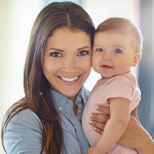 Woman holding a baby in a bright room.