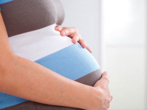 Žena 30. nedelja trudnoće s rukama na stomaku