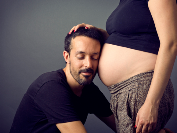 Muž drži glavu na stomaku žene u 35. nedelji trudnoće