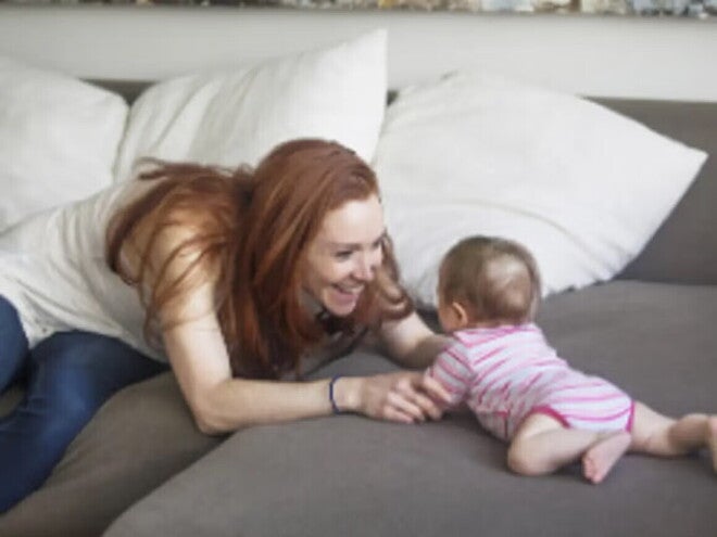 Majka se igra s bebom na krevetu.