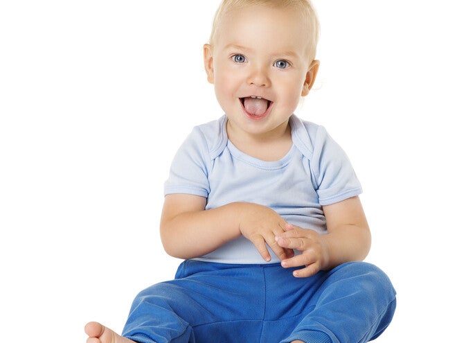 Toddler in blue pants and light shirt, sitting against a white background.