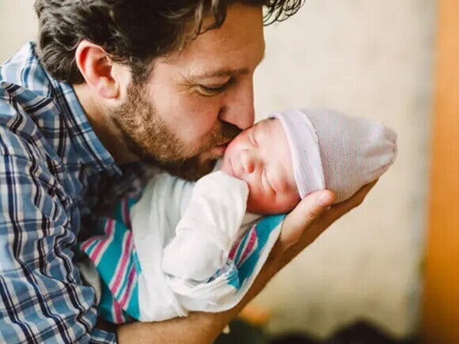 Otac drži novorođenče u naručju.