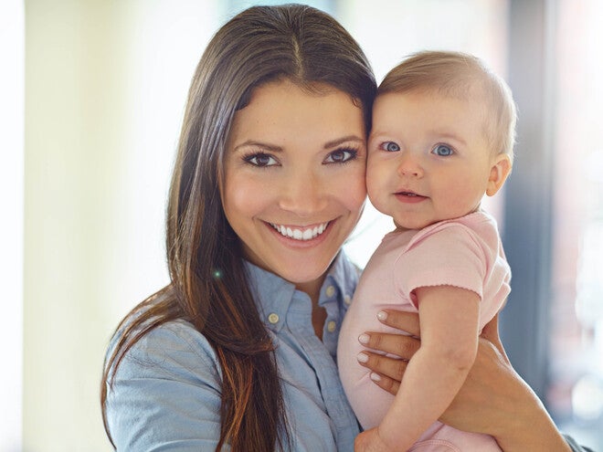 Woman holding a baby indoors.