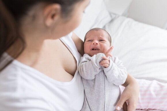 Beba bljucka malu količinu mlijeka nakon hranjenja dok je roditelj drži uspravno.