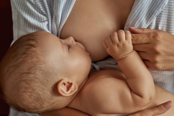 Fotografija bebe koja mirno doji na majčinom grudima.